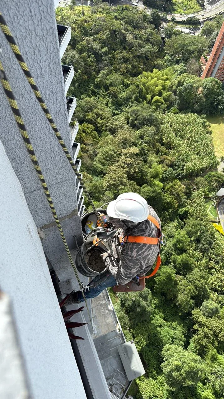 Operario con arnés trabajando en altura en una fachada